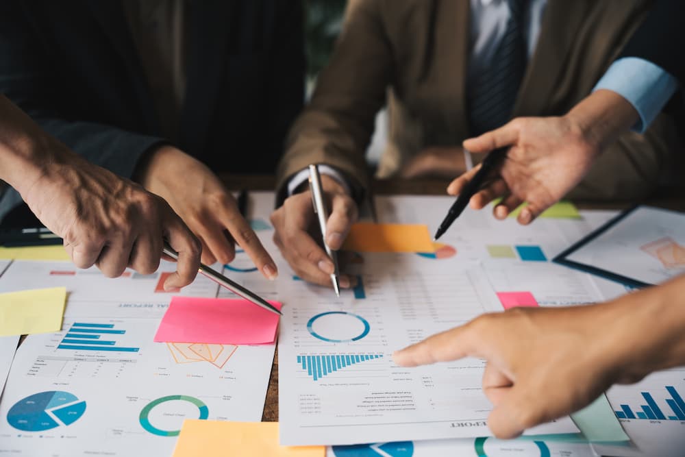 Four people analyzing advertising strategies on a table in a workspace.